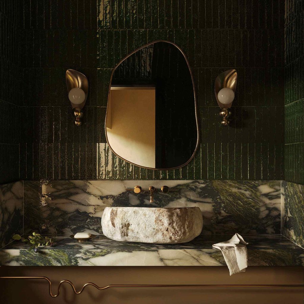 Earthy green marble bathroom with raw stone sink and gold accents