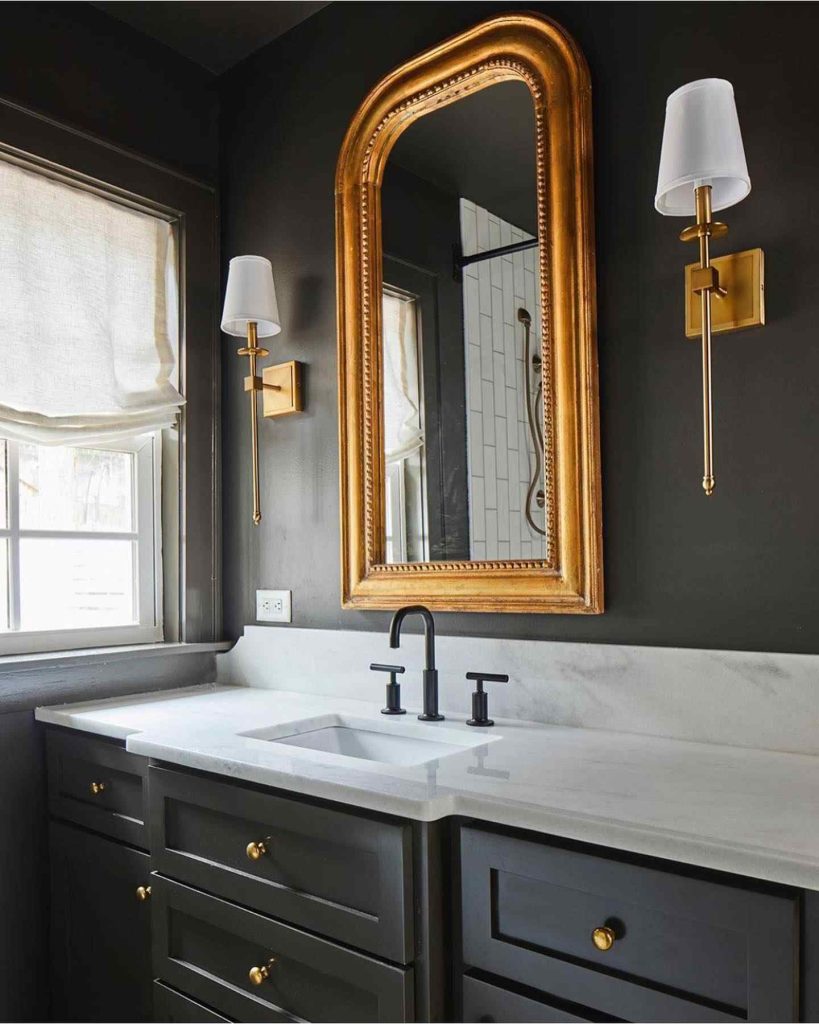 Classic bathroom with gold-framed mirror and dark cabinetry.