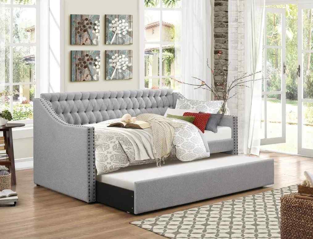 Tufted gray daybed with vibrant accent pillows, set in a bright living room with art on the walls.