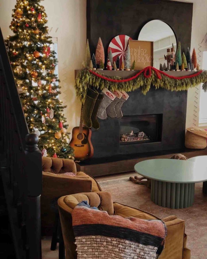 Black fireplace with garlands, stockings, and a lit tree.
