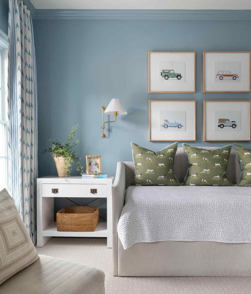 Neutral daybed with dog-themed pillows and vintage car artwork in a light blue room.