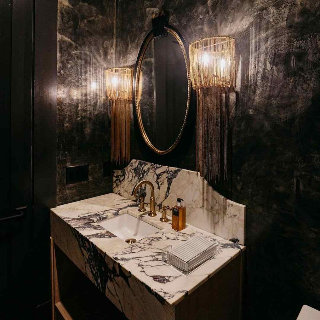 Moody bathroom with fringe sconces and luxurious marble sink