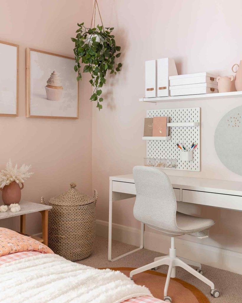 Cozy blush workspace with hanging greenery and soft tones.