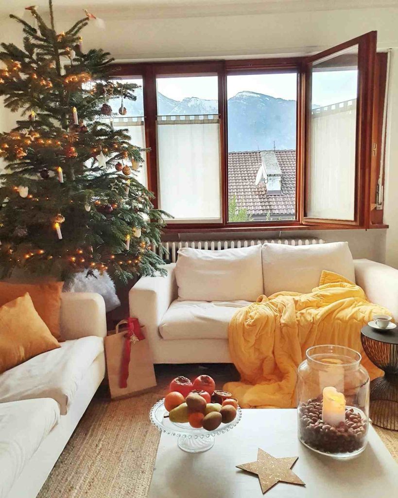 Living room with a lit tree and a mountain window view.
