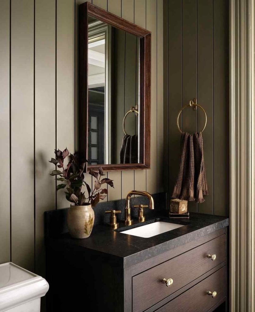 Rustic bathroom with olive paneling, wood vanity, and gold fixtures