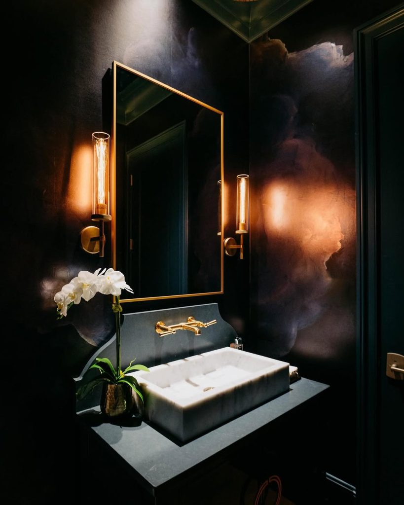 Moody bathroom with abstract dark walls and gold sconces