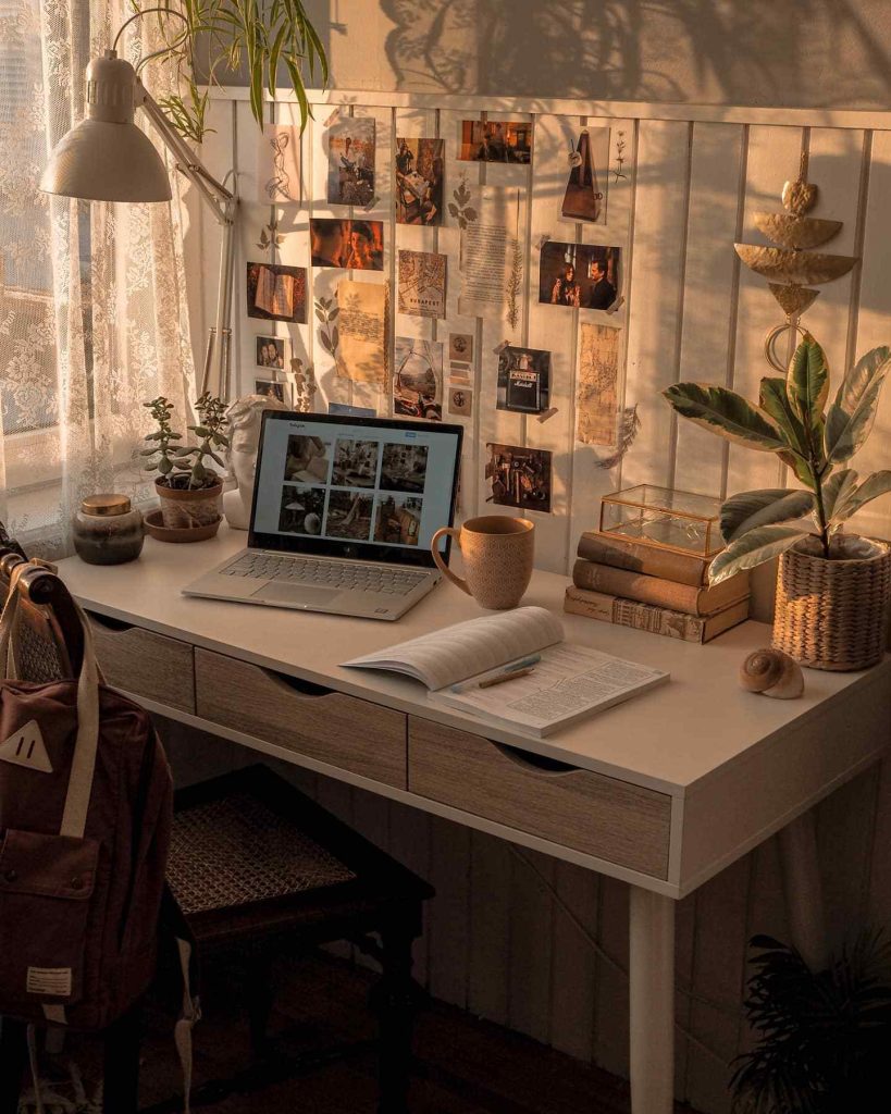 Creative desk with wall collage, coffee, and greenery.