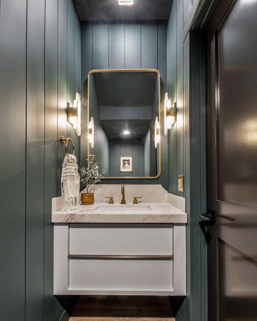 Deep teal bathroom with gold accents and marble countertop.