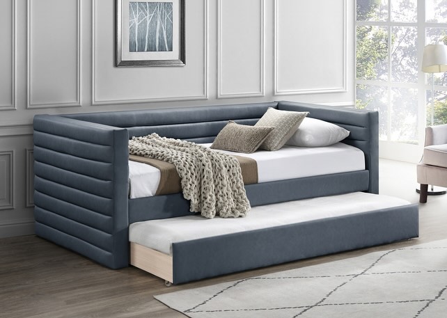 Channel-tufted blue daybed with a pull-out trundle in a modern, neutral-toned room.