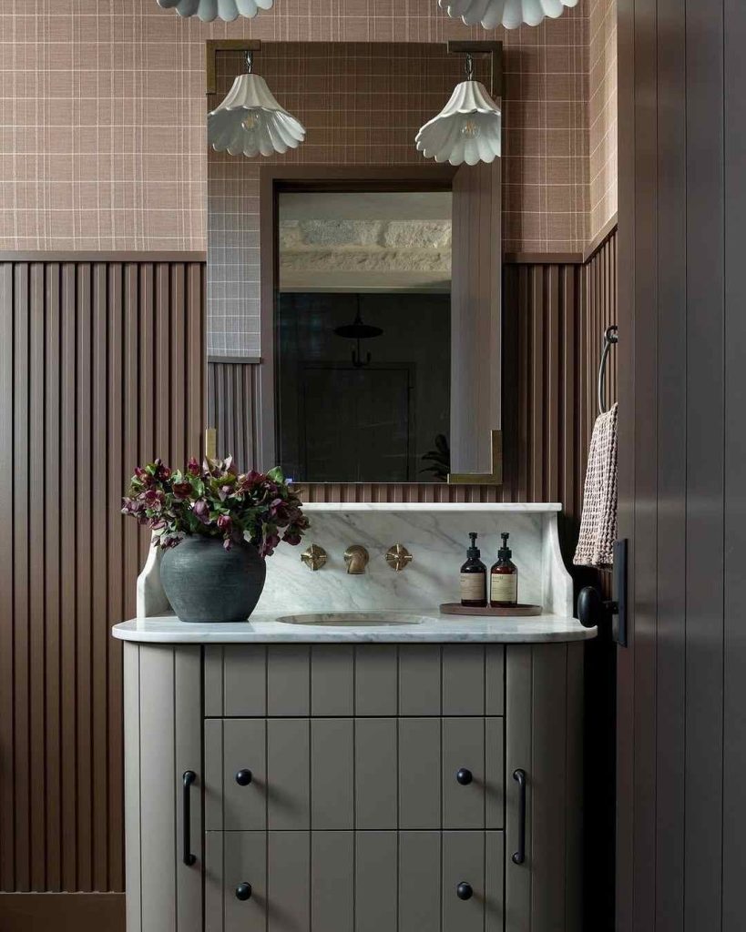 Vintage-inspired bathroom with ribbed paneling and floral lighting.