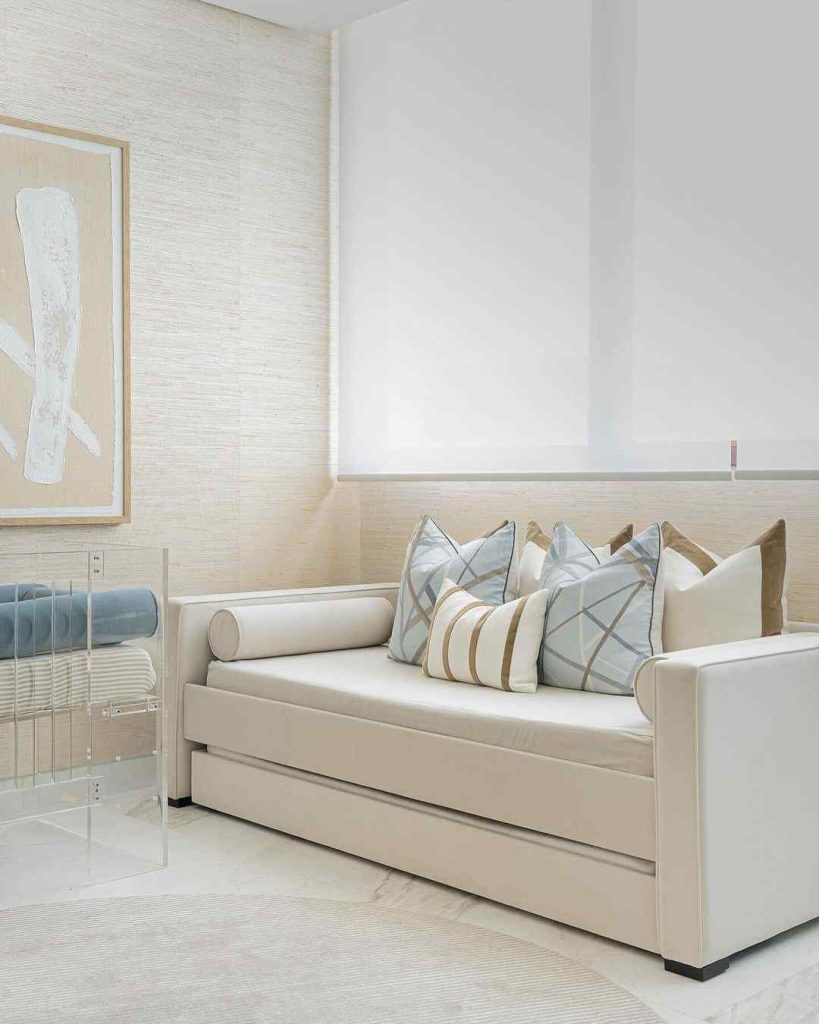  Cream-colored daybed with geometric pillows, set in a neutral, minimalist space with soft lighting.