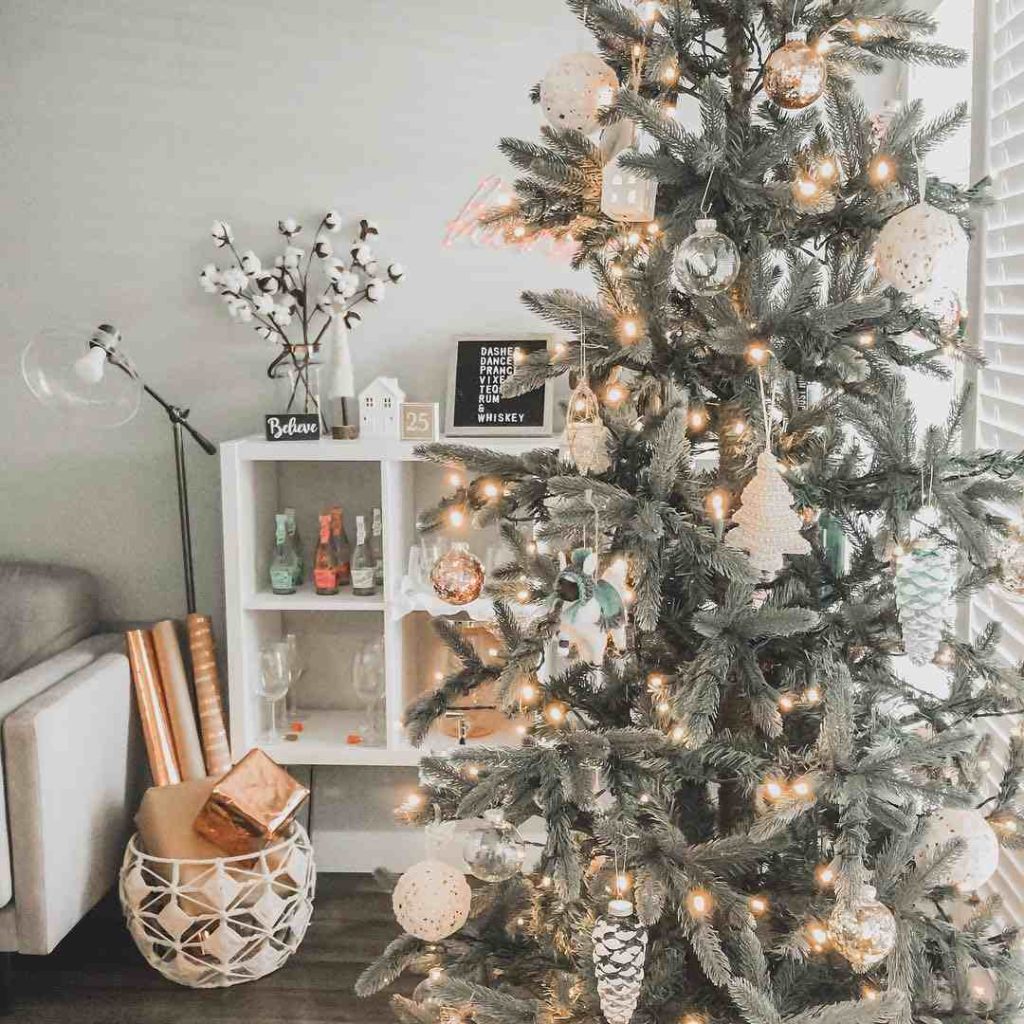 Lit tree with metallic ornaments and a holiday bar cart.
