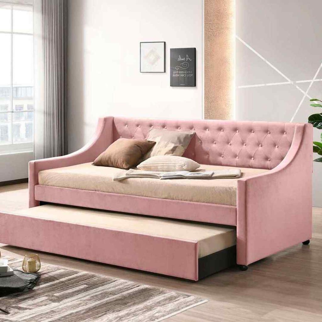  Pink tufted velvet daybed with a trundle, styled with warm-toned bedding and soft lighting.