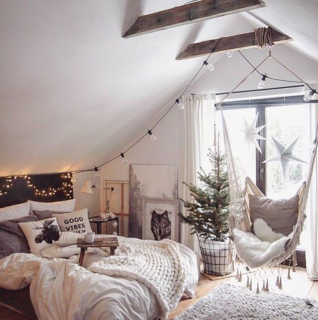 Attic bedroom with string lights and a cozy holiday setup.
