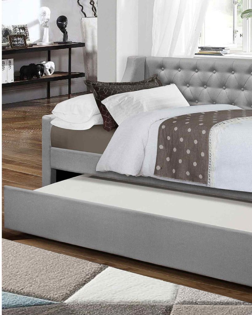 Gray tufted daybed with polka-dot bedding and a trundle, set in a contemporary room.