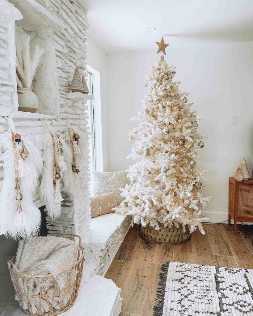 Frosted tree with neutral ornaments and a white fireplace.
