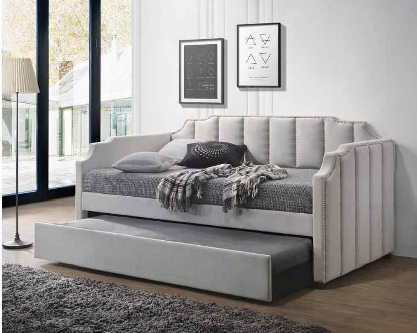 Gray upholstered daybed with a nailhead trim and pull-out trundle, in a modern living room.