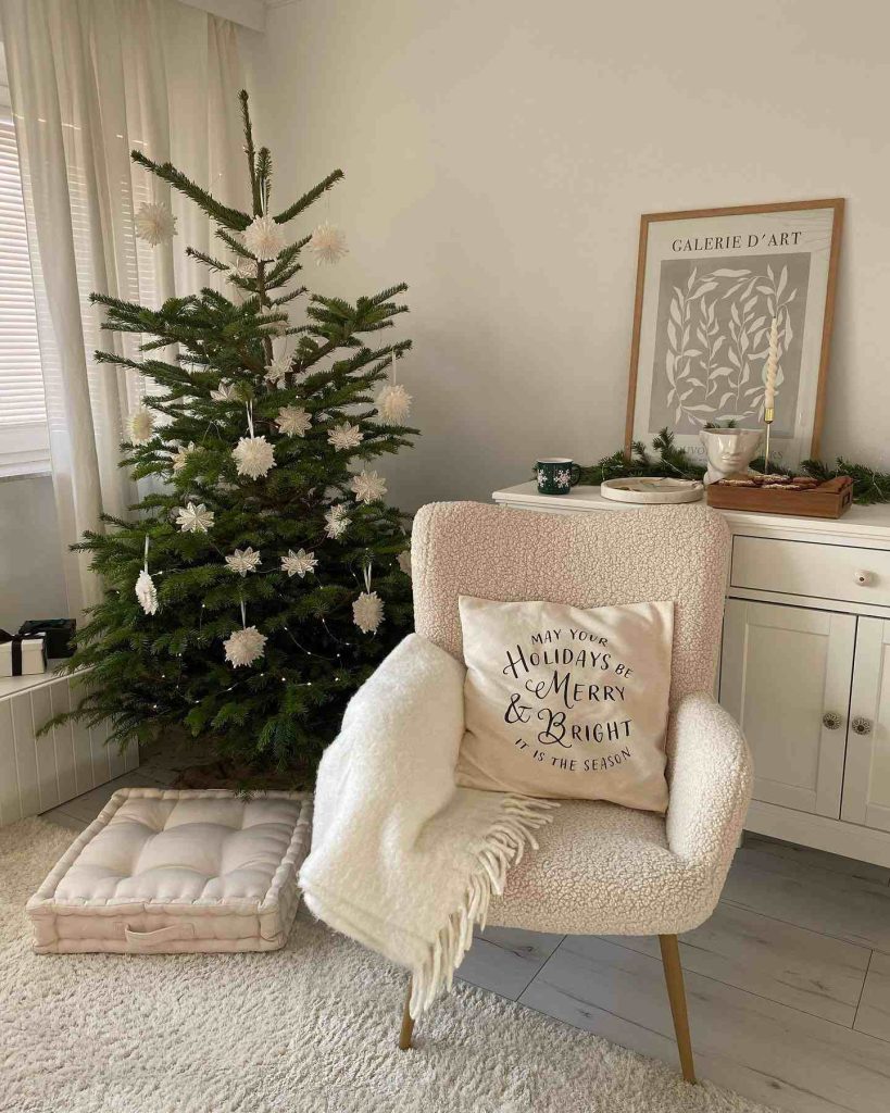 Simple Christmas tree with white ornaments and a cozy chair.
