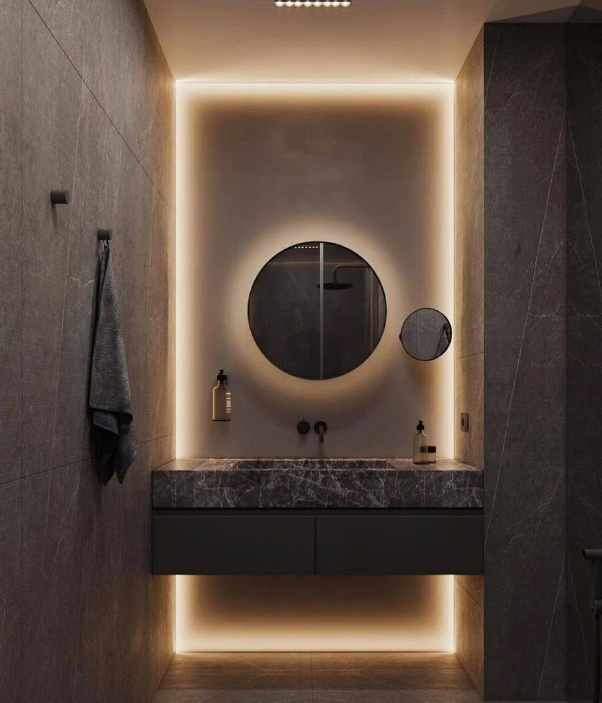 Contemporary bathroom with backlit round mirror and marble vanity