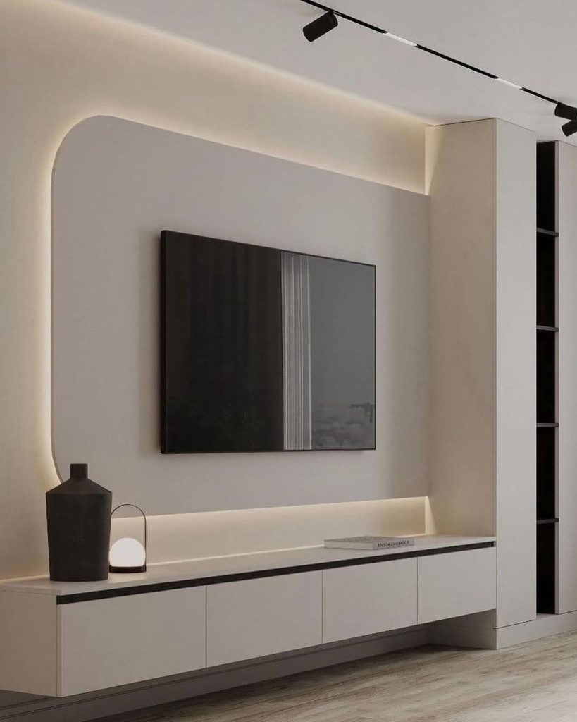 Minimalist TV wall with soft backlighting and sleek white cabinetry.
