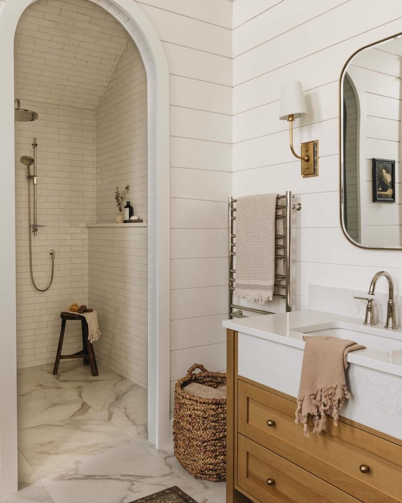 Arched shower nook with warm wood accents and a textured basket.
