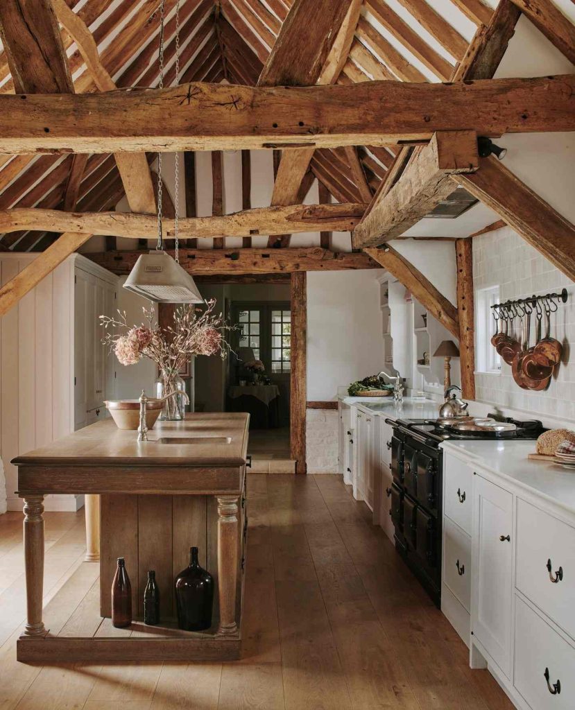 Exposed wooden beams and rustic kitchen with wooden island and white cabinets.
