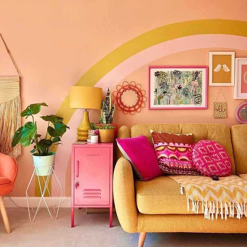 Colorful living room with mustard sofa, rainbow wall art, and vibrant decor.