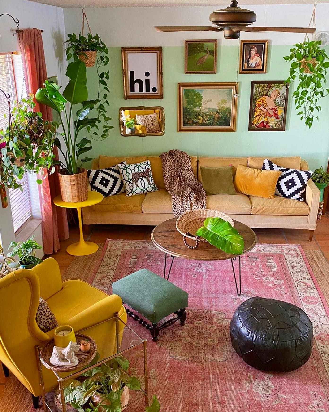 Boho-style living room with lush plants, mustard and green accents, and pink rug.
