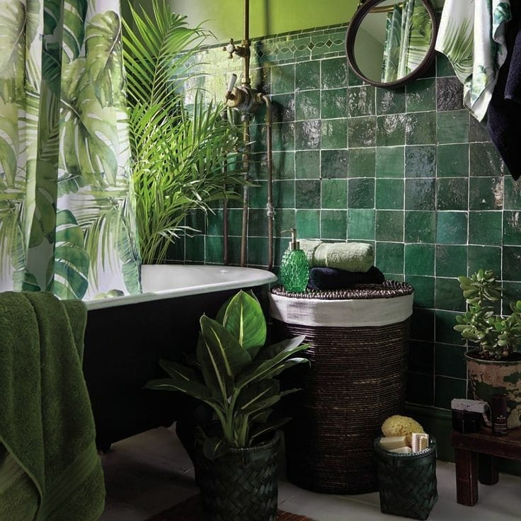 Tropical-inspired bathroom with emerald green tiles, leafy plants, and natural accents.
