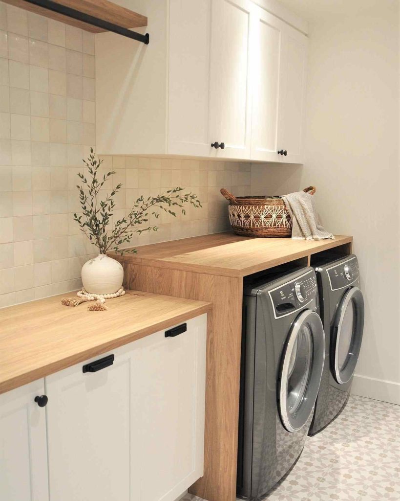 Organized gray laundry room with open shelves, woven baskets, and greenery.
