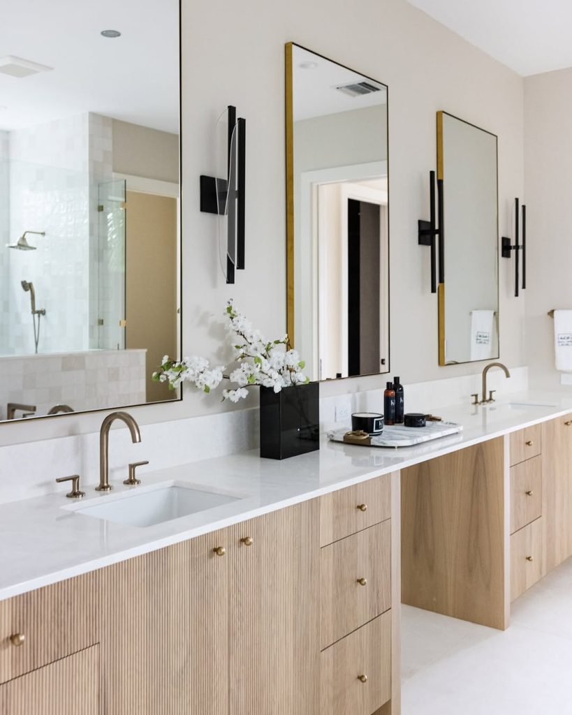 Modern bathroom with gold fixtures and ribbed wood cabinetry.
