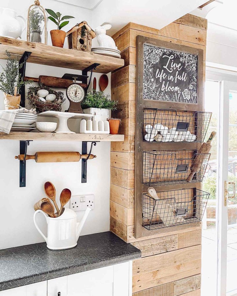 Charming rustic kitchen corner with open shelves, wire baskets, and a chalkboard sign.
