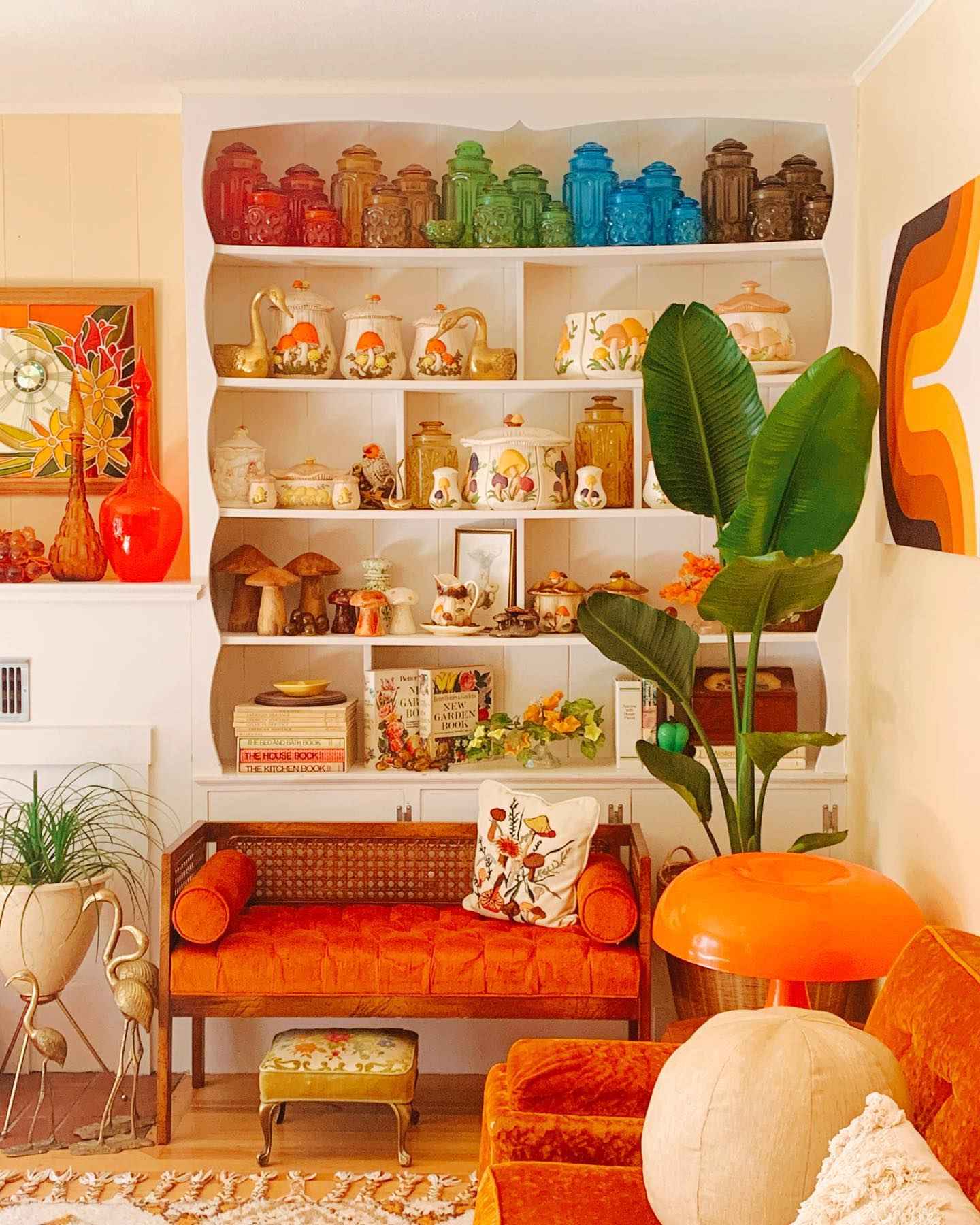 Vintage-inspired room with orange velvet seating and rainbow glass jar shelves.
