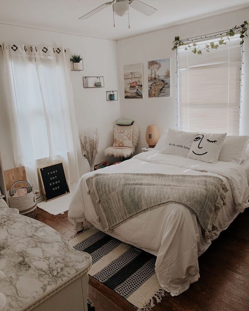 Bright white bedroom with soft decor, personal wall art, and natural lighting.