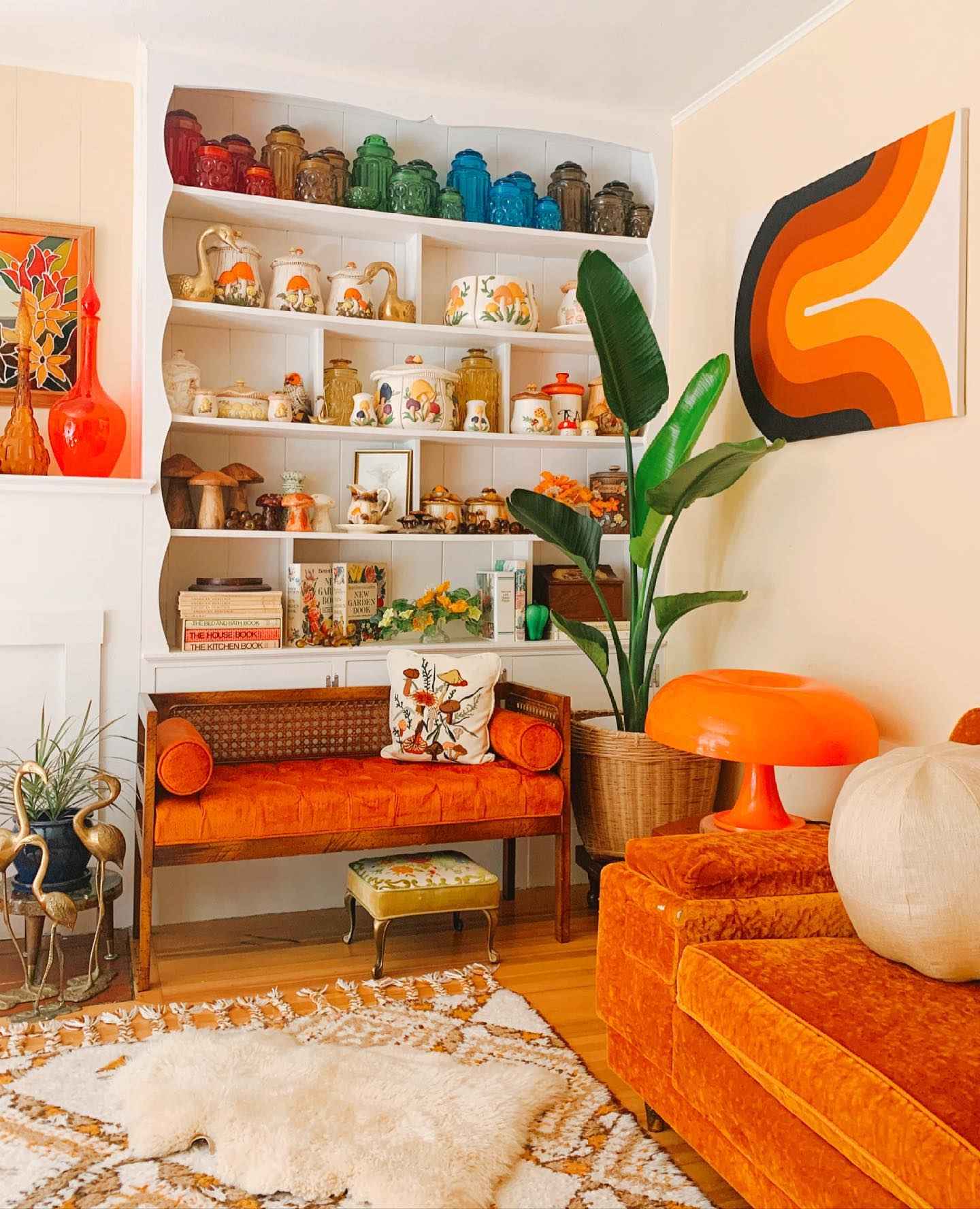 Retro living room with orange accents, bold artwork, and cozy textures.
