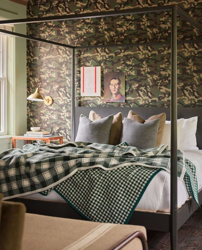 Bold bedroom with camouflage wallpaper, plaid bedding, and modern accents.