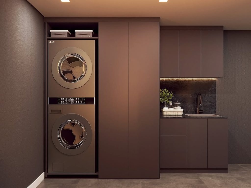 Green and gold laundry room with open wood shelves and floral wallpaper.
