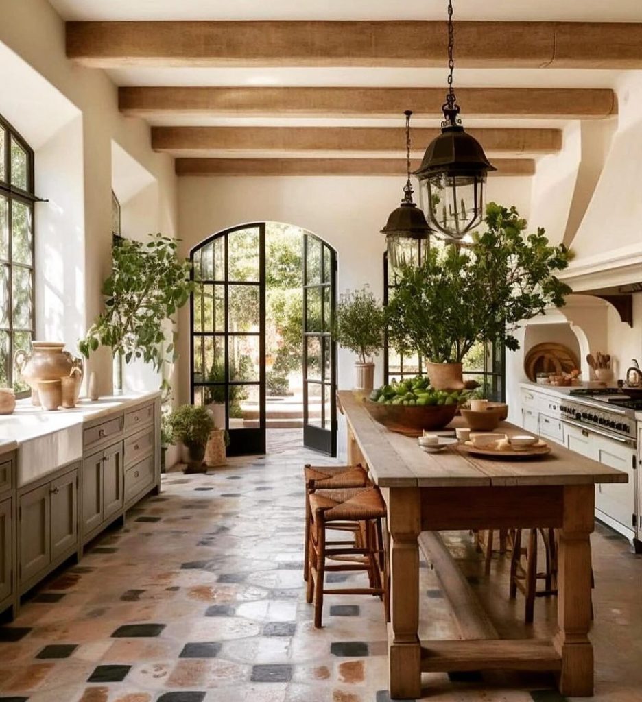 Mediterranean-style kitchen with large arched doors, terracotta tiles, and a wooden table.
