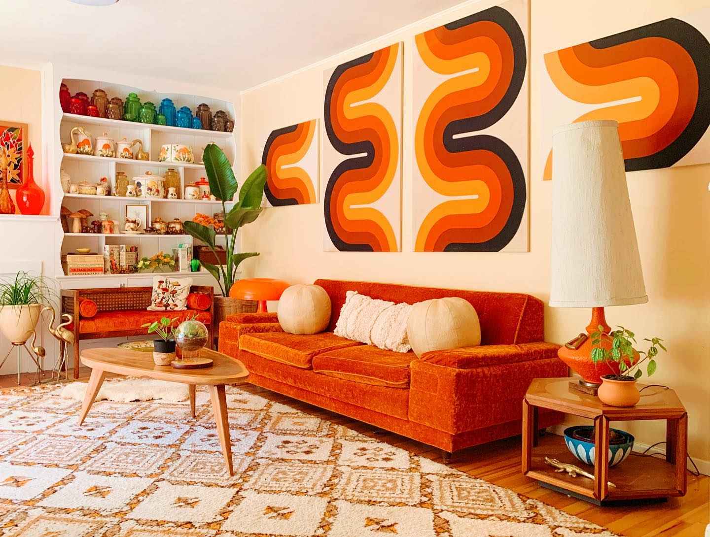 Groovy orange-themed living room with shag rug and bold wall art panels.
