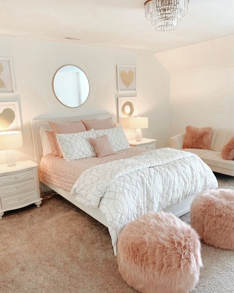 Chic blush and white bedroom with a fluffy rug and sparkling chandelier.