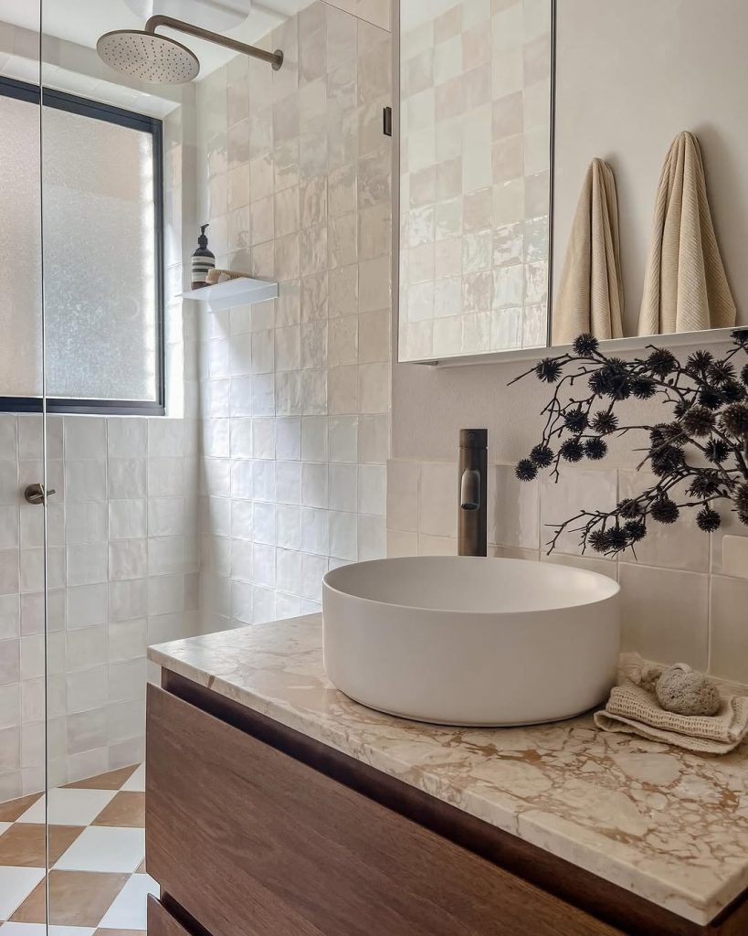 Textured tile shower with marble countertops and a wood vanity.
