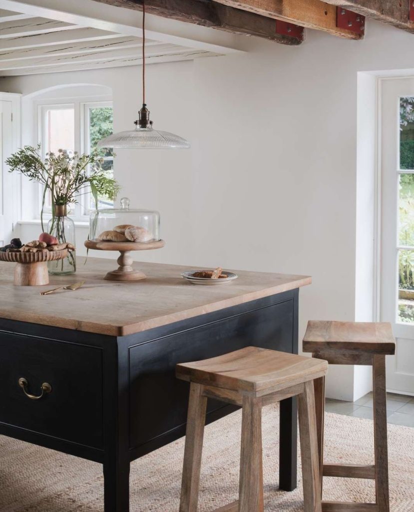 Minimalist rustic kitchen island with black base, natural wood countertop, and simple stools.
