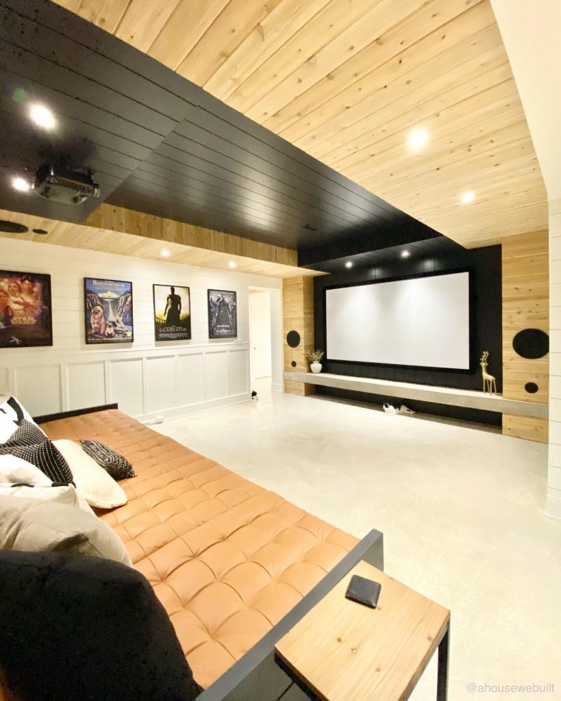 Home theater with wood paneling, large screen, and tufted seating.
