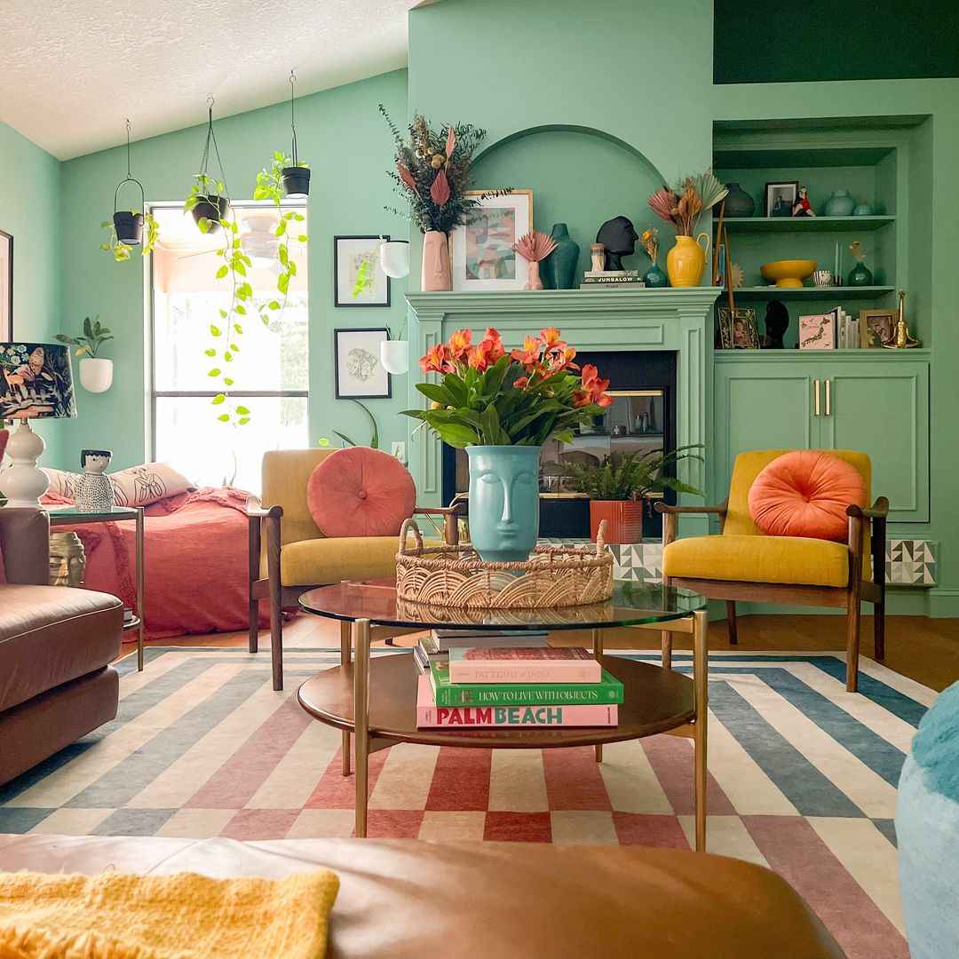 Mint green living room with colorful accents, hanging plants, and a bold rug.
