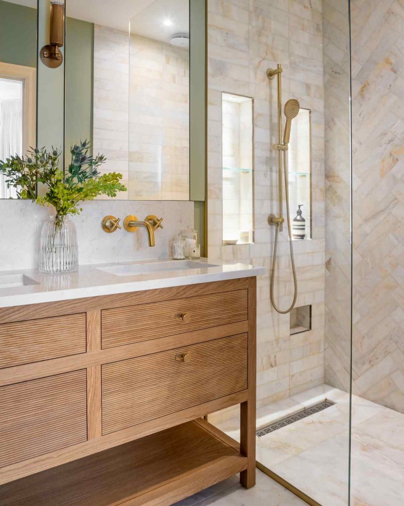 Gold fixtures in a serene bathroom with a natural wood vanity.
