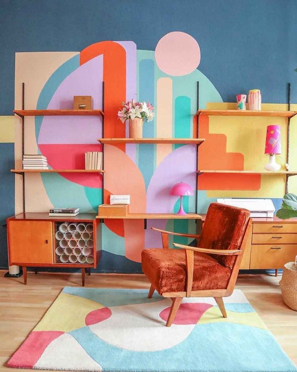 Mid-century living room with a bold geometric mural and retro orange chair.
