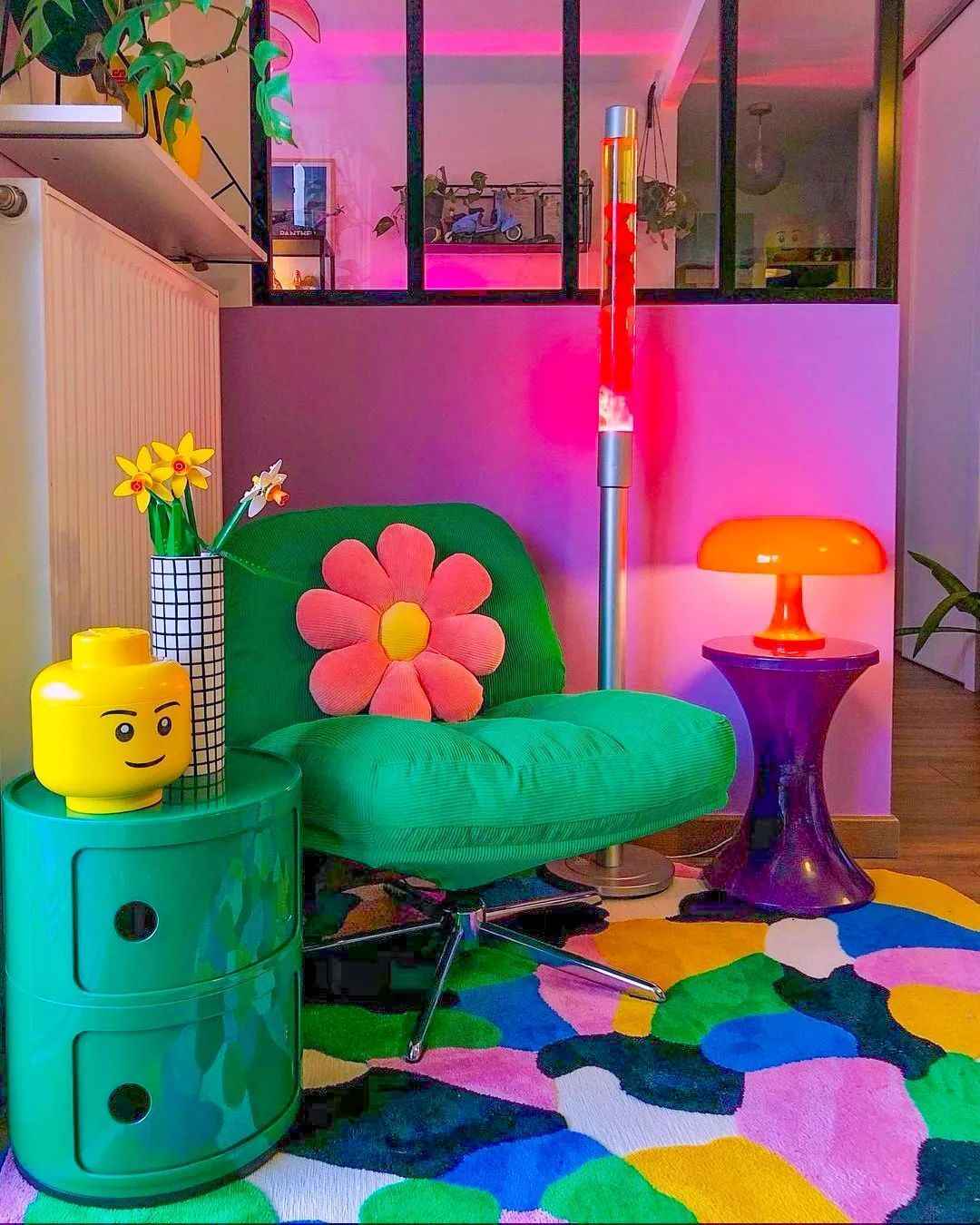 Playful corner with bold green chair, flower pillow, and colorful lava lamp.
