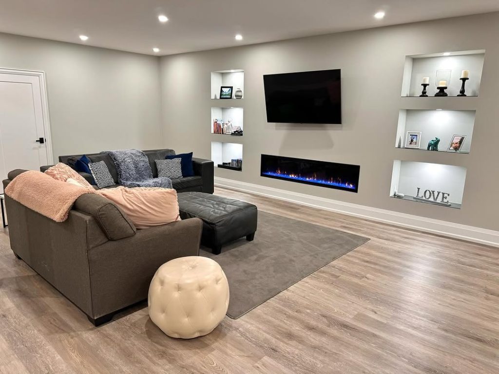 Cozy basement TV room with recessed shelves and a sleek fireplace.
