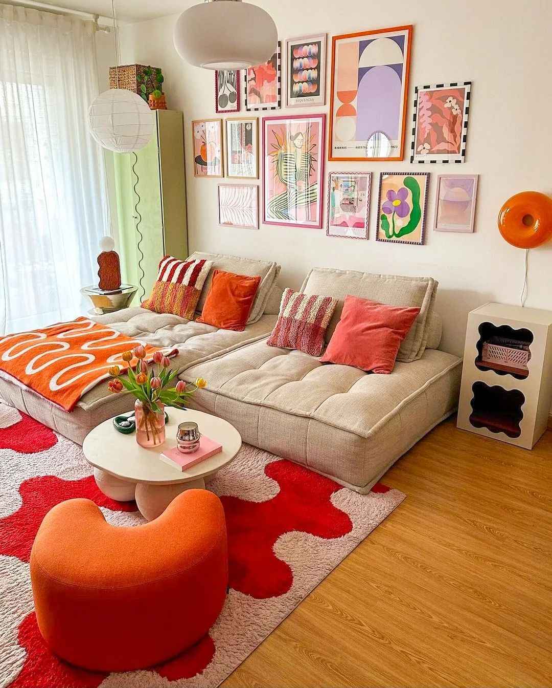 Creative space with tufted seating, red wavy rug, and bold patterned gallery wall.