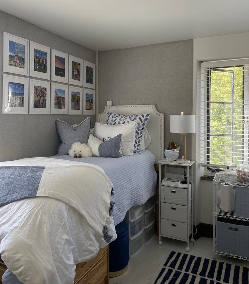 Compact bedroom with soft blue tones, photo collage wall, and cozy decor.